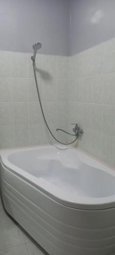 uma banheira branca com uma mangueira ligada a uma parede em Квартира em Samarkand