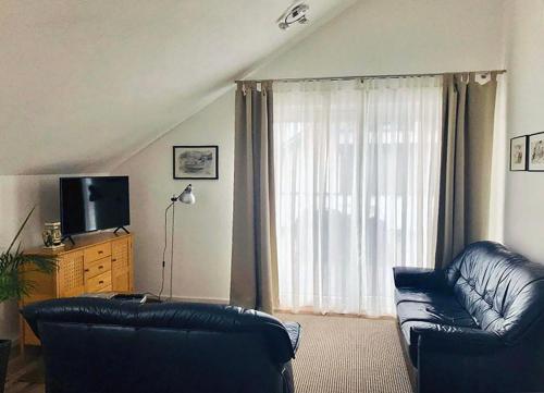 un salon avec un canapé en cuir noir et une télévision dans l'établissement FERIENWOHNUNG SEEBRISE mit sonniger Dachterrasse, à Uhldingen-Mühlhofen