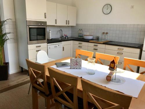 une cuisine avec une table et des chaises et une cuisine avec une horloge dans l'établissement FERIENWOHNUNG SEEBRISE mit sonniger Dachterrasse, à Uhldingen-Mühlhofen