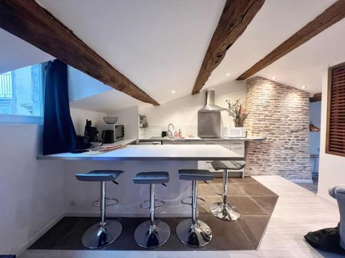 une cuisine avec trois tabourets de bar et un comptoir dans l'établissement L'Atypique - Coeur de ville, à La Rochelle