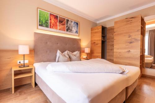 Schlafzimmer mit einem großen weißen Bett und Holzwänden in der Unterkunft Hotel Castel - pure Lebensfreude in Serfaus
