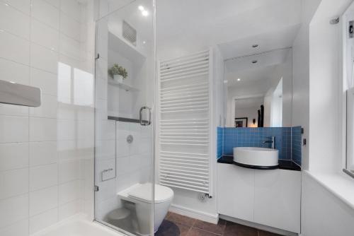 a white bathroom with a toilet and a sink at King's Cross Penthouse by MoreThanStays in London