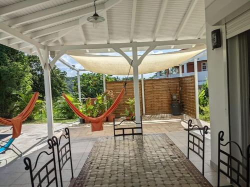a pavilion with chairs and hammocks on a patio at Coquette villa avec piscine proche des plages in Sans Pareil