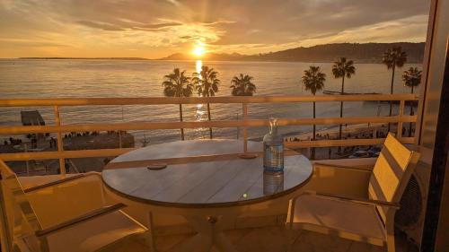 una mesa y sillas en un balcón con vistas a la puesta de sol en Superbe appartement vue mer panoramique, en Juan-les-Pins