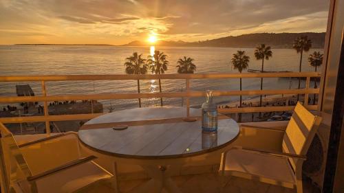 ジュアン・レ・パンにあるSuperbe appartement vue mer panoramiqueの夕日を望むバルコニー(テーブル、椅子付)