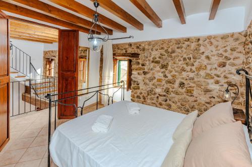 1 dormitorio con cama y pared de piedra en Villa Can Abrines, en Lloseta