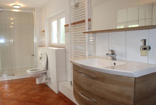 a white bathroom with a sink and a toilet at Ferienhaus Naturliebe 6000qm Parkgarten am Wald, umzäunt, Kamin, Sauna in Laubach