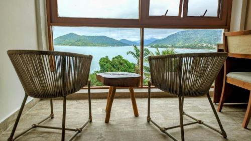 two chairs and a table in front of a window at Catalina Hotel in Ubatuba