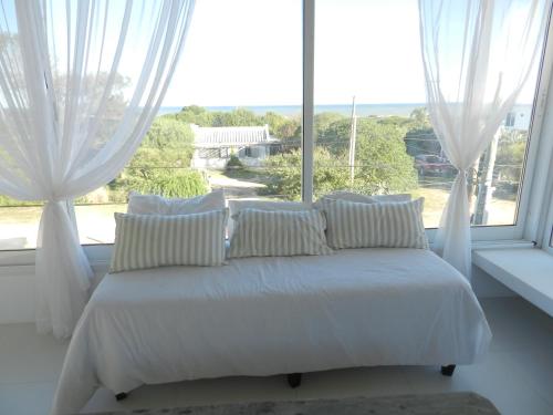 a bed with white sheets and pillows in front of a window at Malujoseignacio in José Ignacio