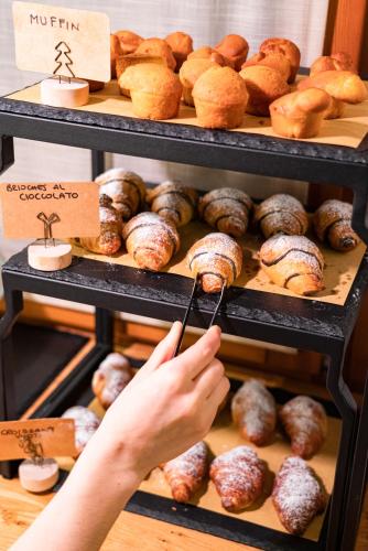 una persona sta prendendo un dolce da una vetrina di Hotel Alla Corte SPA & Wellness Relax a Bassano del Grappa