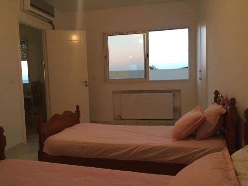 1 dormitorio con 2 camas con almohadas y ventana en Appartement pied dans l eau ,diamond bleu s+1 en Sousse