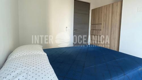 a bedroom with a bed with a blue comforter at Lujo en Crystal Lagoons: Paraíso para la familia. in Mazatlán