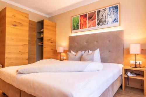 a bedroom with a large white bed with two lamps at Hotel Castel - pure Lebensfreude in Serfaus