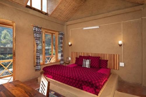 a bedroom with a large red bed in a room at Living Good - A Himalayan Boutique Stay in Gushaini