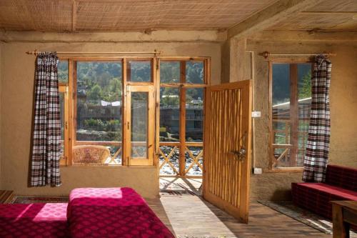 Cette chambre dispose d'un canapé et d'une fenêtre avec vue. dans l'établissement Living Good - A Himalayan Boutique Stay, à Gushaini