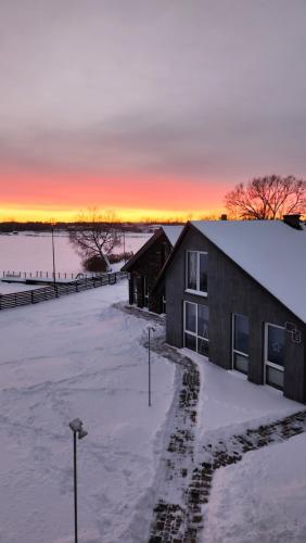 a house in the snow with the sunset in the background at Add Story Guest House in Rēzekne