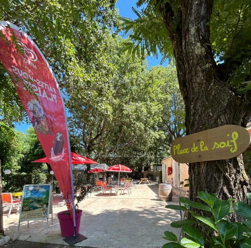 un panneau sur un arbre à côté d'un café dans l'établissement Camping Beaussement TWENTY, à Chauzon