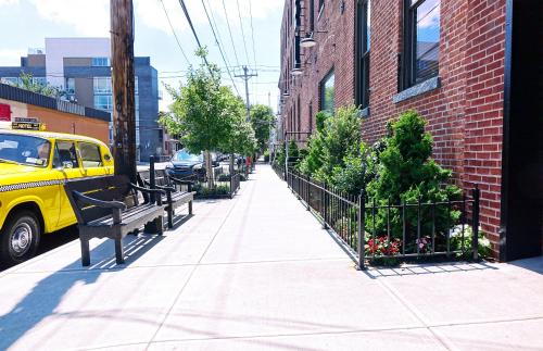 a sidewalk with benches and a yellow van parked next to a building at Henry Norman Hotel in Brooklyn