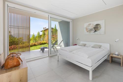 a white bedroom with a bed and a balcony at Residence Conca Verde 1 with pool in Trarego Viggiona