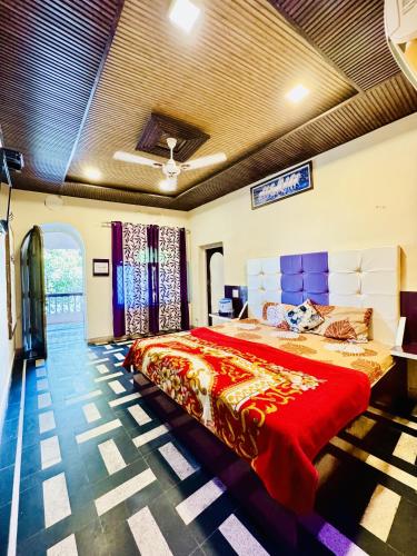 Hotel New Sun N Rock ( 1km from Nakki Lake ) في مونت ابو: غرفة نوم بسرير كبير مع بطانية حمراء