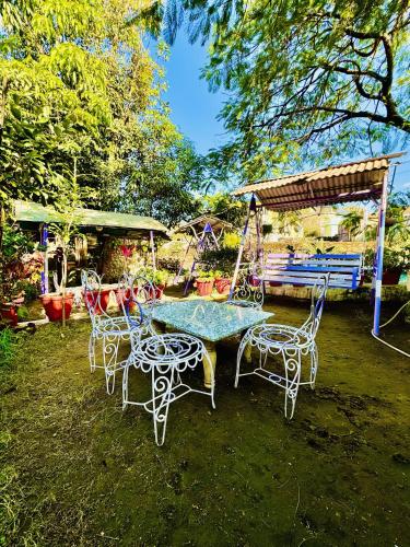 een tafel en stoelen in een tuin met een schommel bij Hotel New Sun N Rock ( 1km from Nakki Lake ) in Mount Ābu