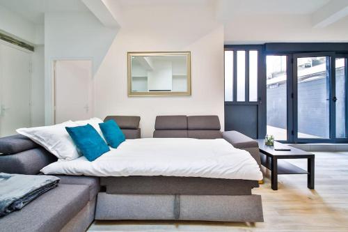 - une chambre avec un lit et un canapé avec des oreillers bleus dans l'établissement Jolie appartement près du métro, à Montrouge
