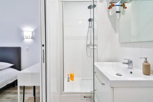 une salle de bain blanche avec un lavabo et un miroir dans l'établissement Jolie appartement près du métro, à Montrouge