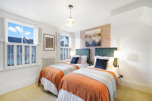 twee bedden in een kamer met ramen bij Lux 3 Bed London House - Garden in Londen