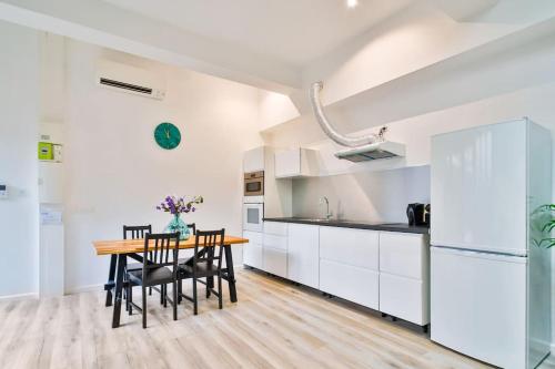 - une cuisine et une salle à manger avec des placards blancs et une table en bois dans l'établissement Jolie appartement près du métro, à Montrouge