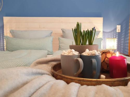 a table with two cups and a potted plant and a candle at FeWo Winter in der Villa Waldrand mit zwei Balkonen in Bad Wünnenberg