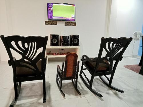 2 sillas negras sentadas en una habitación con TV en Cabaña Rochy, en Coveñas