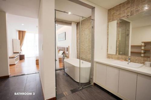 a bathroom with a tub and a sink and a mirror at Modern & Charming Penthouse 5BRs in Da Nang Center in Da Nang
