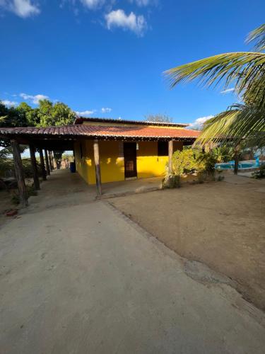 a yellow house with a palm tree in front of it at Chácara Tantan - Martins RN in Martins
