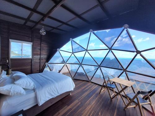 a bedroom with a large window with a bed and a chair at 321 Surprise Beach house and Glamping in Providencia