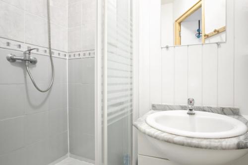 une salle de bain blanche avec un lavabo et une douche dans l'établissement A 2 pas de la mer - Plage à 50m, à Barneville-Carteret