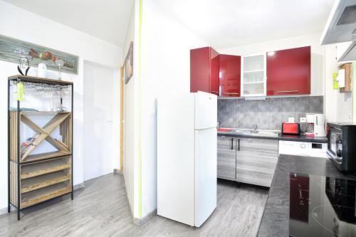 La cuisine est équipée d'un réfrigérateur blanc et de placards rouges. dans l'établissement A 2 pas de la mer - Plage à 50m, à Barneville-Carteret