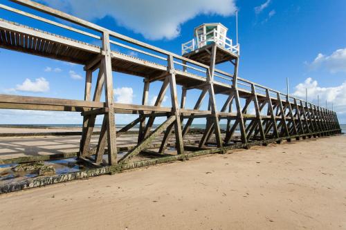 a pier with a lifeguard tower on the beach at Les 7 lutins - Maison avec jardin, wifi, parking in Luc-sur-Mer