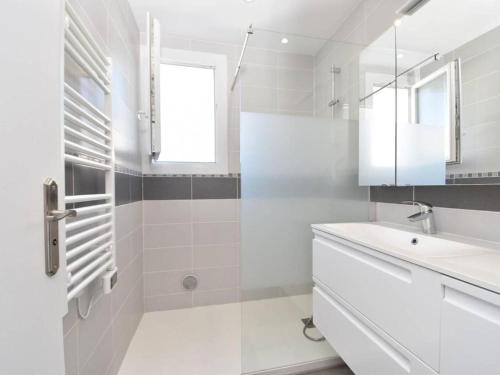 W białej łazience znajduje się umywalka i lustro. w obiekcie T3 moderne au Grau du roi w mieście Le Grau-du-Roi