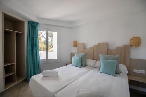 1 dormitorio con 1 cama blanca grande con almohadas azules en MarSenses Ferrera Blanca Hotel Family en Cala d´Or