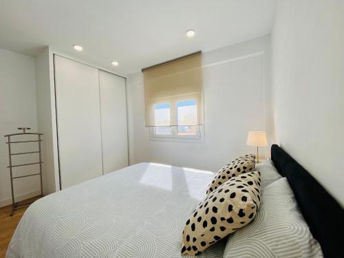 a white bedroom with a large bed with pillows at Apartamento HC13 - PUERTA PURCHENA in Almería