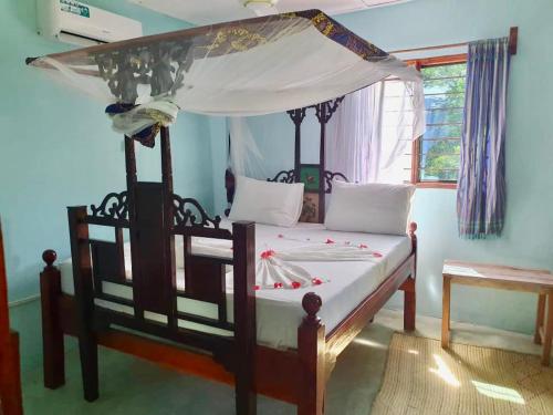 a bedroom with a wooden bed with a canopy at Mustapha' s Place in Bwejuu