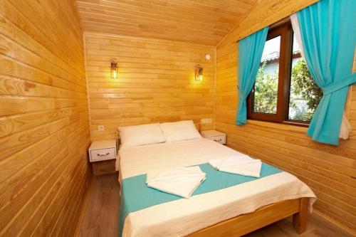 ein Schlafzimmer mit einem Bett in einem Holzzimmer in der Unterkunft Eliz Apart & Bungalow in Kumluca