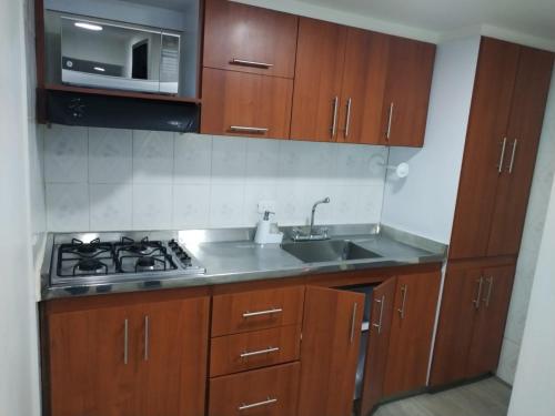 a kitchen with wooden cabinets and a sink and a microwave at HOTEL SALITRE STAR in Bogotá