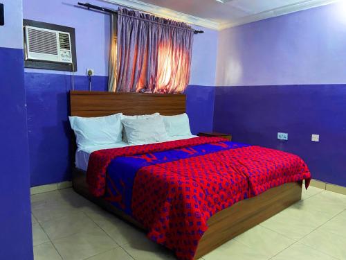 een slaapkamer met een bed met een rode en blauwe deken bij Suofega Hotel and Suites in Ughelli