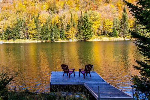 two chairs sitting on a dock in the middle of a lake at Eko Eau Chalet An Outstanding view that will delight you in Saint Adolphe D'Howard