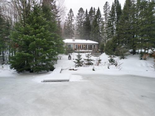 a house in a snow covered yard with trees at Eko Eau Chalet An Outstanding view that will delight you in Saint Adolphe D'Howard