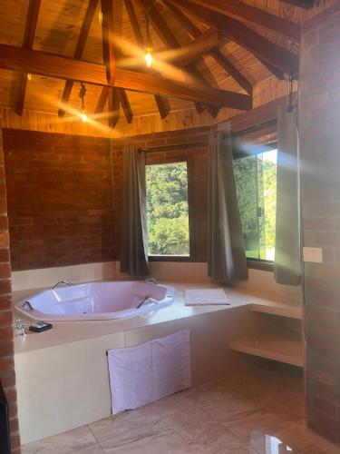 uma grande banheira num quarto com janelas em Pousada do valle em Monte Verde