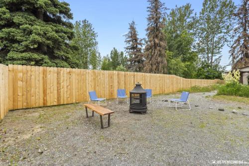 een vuurplaats met stoelen, een bank en een hek bij The Glacial Cottage Slumber Village 9 in Anchorage