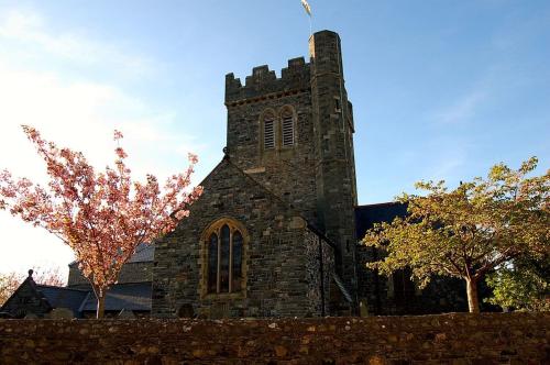 an old stone church with a tower with a tree at Y Bwthyn Bach Cute Stone Cottage in Tywyn in Tywyn