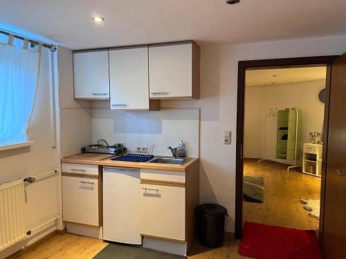 a small kitchen with white cabinets and a sink at Cozy Flat near Maastricht Heerlen Aachen in Übach-Palenberg